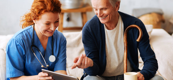 female nurse and senior man are laughing while watching at the tablet device