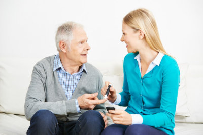 caregiver measuring blood sugar in a senior man with diabetes