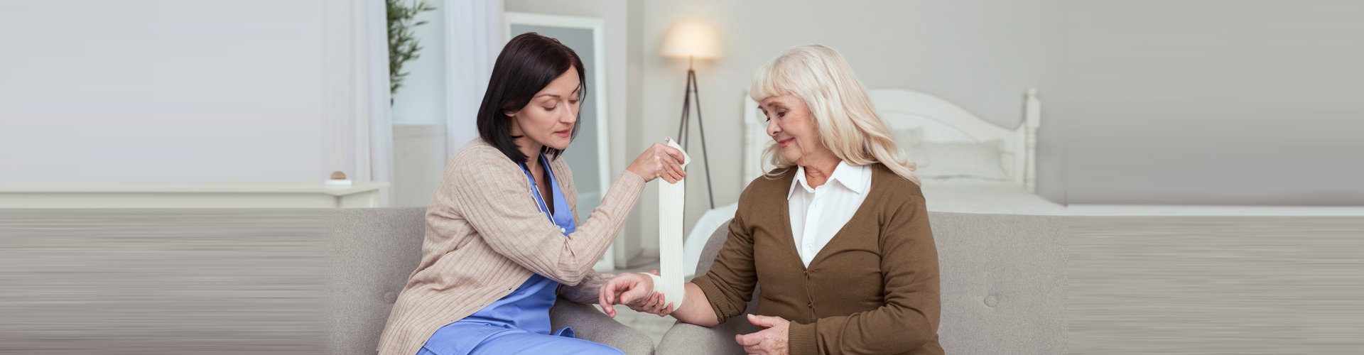 caregiver putting a bandage to the senior woman with injured arm