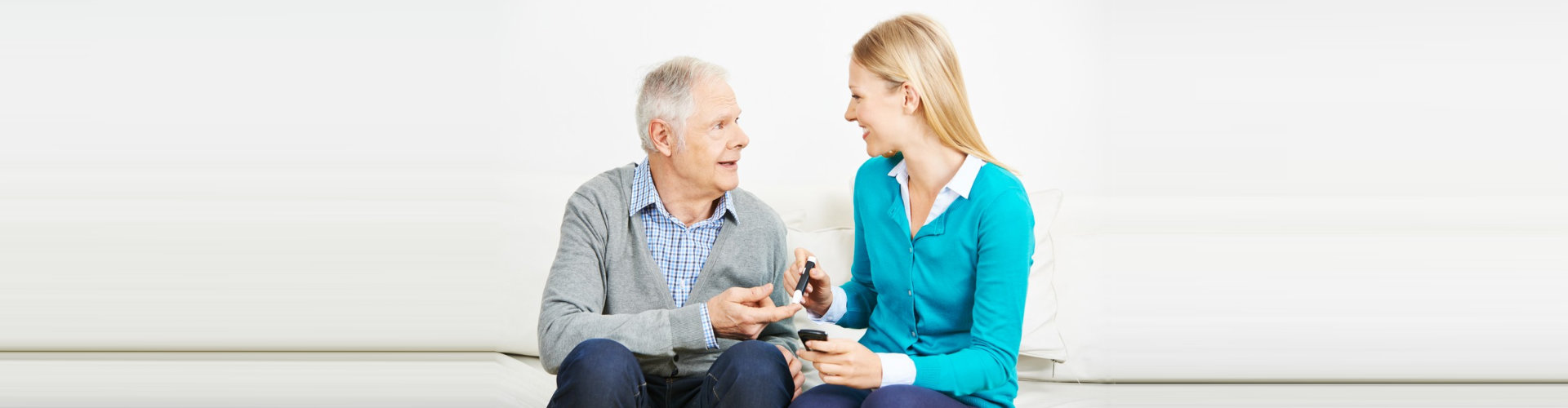 caregiver measuring blood sugar in a senior man with diabetes