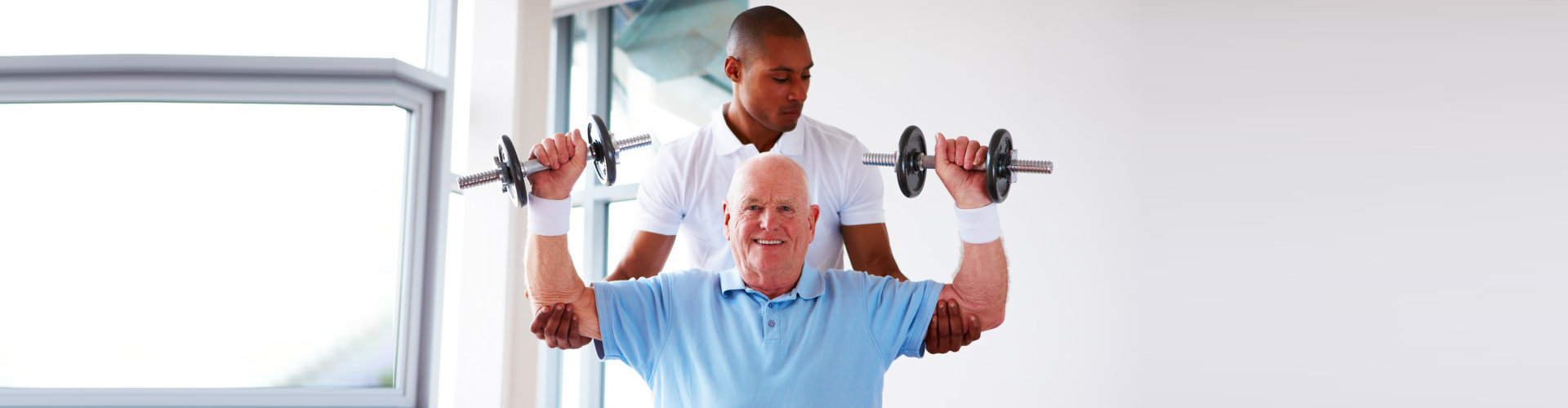 gym instructor assisting senior man doing an exercise